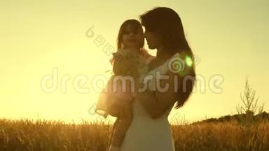 妈妈和小女儿正在一片成熟的麦子上玩耍。 母亲带着一个孩子在一片小麦的田野里散步。 开心快乐